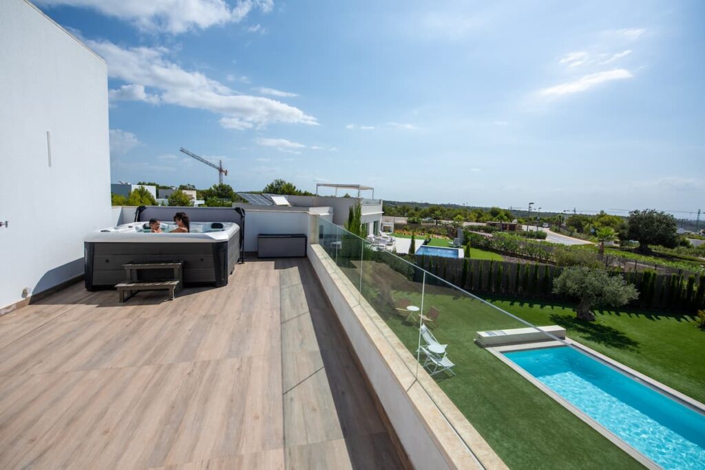 A Platinum Spas hot tub on a terrace in Spain. There is a swimming pool below the terrace.