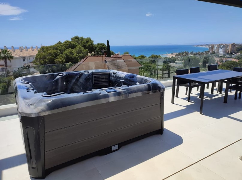 A Barcelona hot tub in the Odyssey colour, on a terrace with a sea view.